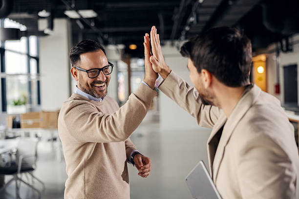 istock Businessmen celebrating success with high five in office 2245556546