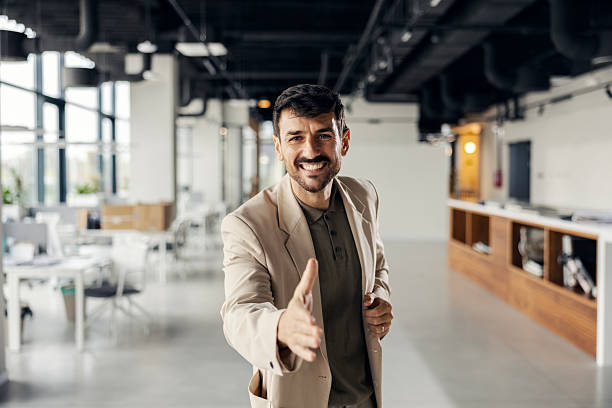 istock Businessman extending hand for handshake in modern office 2245557620