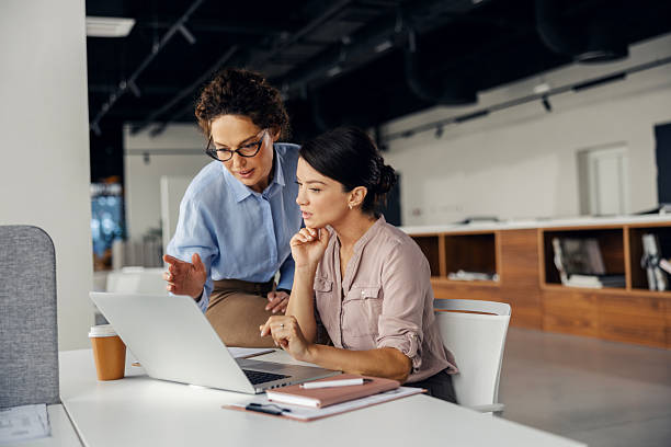istock Businesswomen collaborating on laptop in modern office 2245557791
