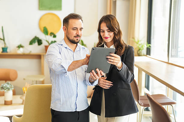 istock Smiling business colleagues discussing project on digital tablet in modern office 2245558990