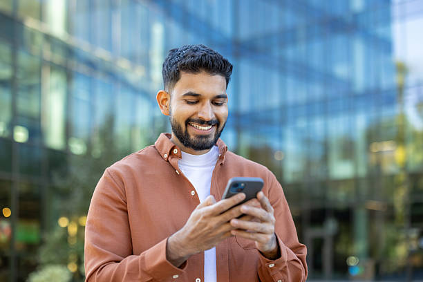 istock Young man smiling, browsing on smartphone in city 2245561348