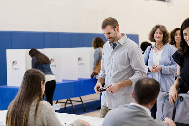 istock Adults wait in line to cast their votes at a polling station inside. 2245563879