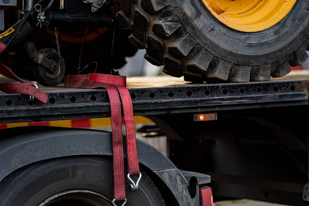 istock Heavy machinery wheel secured on transport trailer using red ratchet straps, illustrating construction equipment logistics, load safety, industrial transport and mechanical cargo securing system detail 2245564468