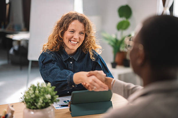 istock Smiling woman shaking hands in a bright office 2245566395
