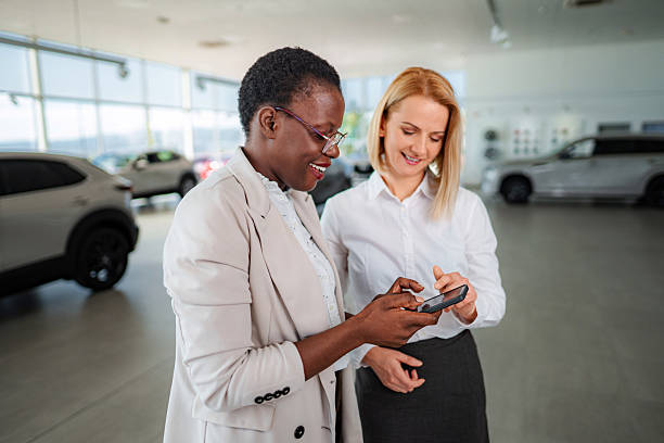 istock Two women using smartphone in car dealership during sales process 2245566478