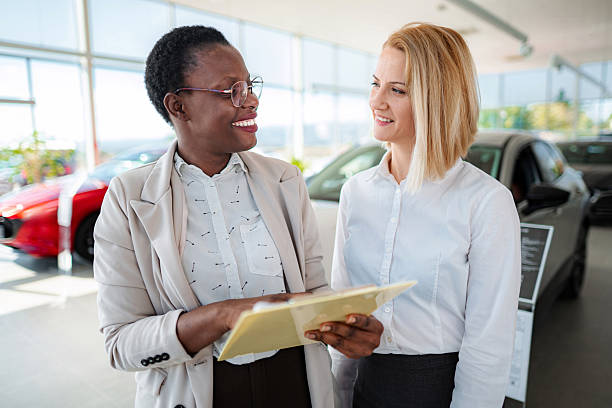 istock Car saleswoman explaining documents to customer in showroom 2245566711