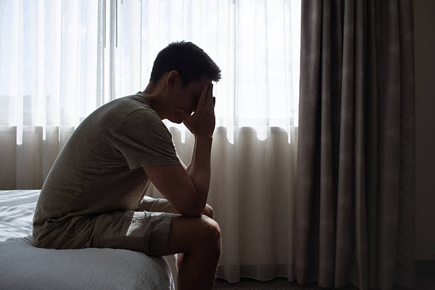 istock Stressed Man Sitting Alone Indoors with Head in Hands 2245567622