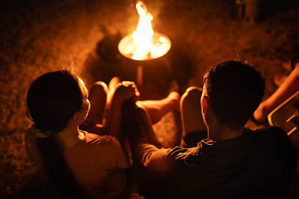 istock Couple Sitting by a Warm Campfire at Night 2245567628