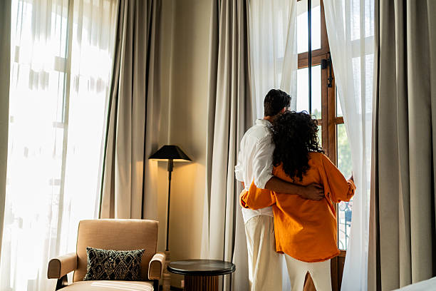 istock Young couple looking through window at hotel room 2245567857