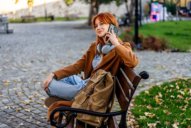 istock Young woman talking on phone in park 2245570568