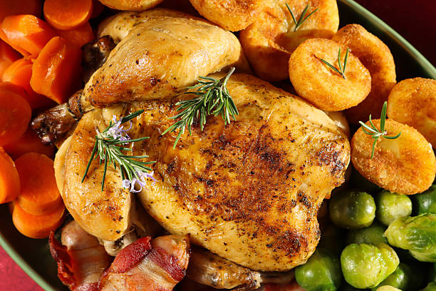 istock Full frame image Sunday roast dinner with all the trimmings on green serving dish, whole roast chicken with crispy, golden skin garnished with Rosemary sprigs, surrounded by side dishes of Brussel sprouts, roast potatoes, sliced carrots, pigs in blankets 2245573396
