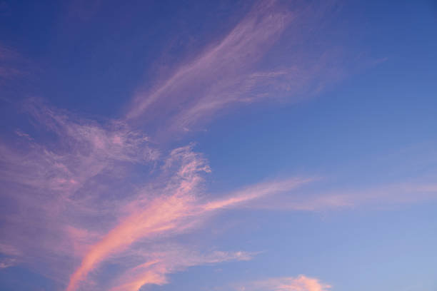 The pink of the sunset blends with the blue of the night, creating a dramatic skyscape, and the abstract patterns of the flowing clouds create a sense of tranquility and the extraordinary.