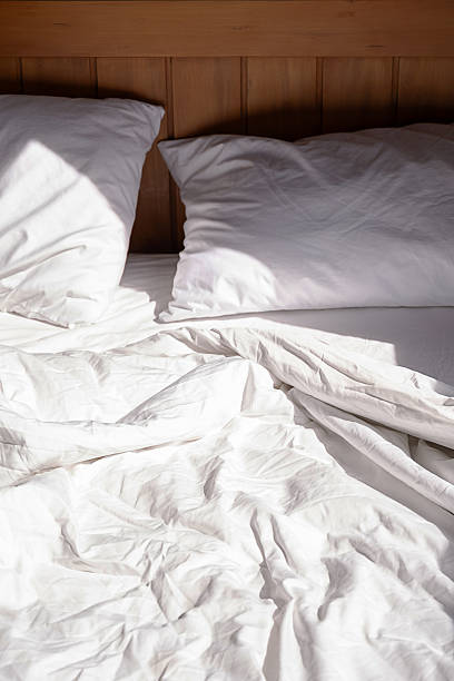 istock Unmade bed with white linen in sunlight. Cozy morning scene. 2245582764