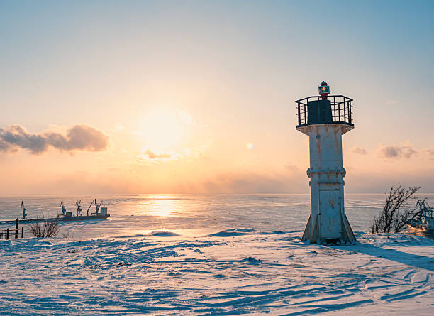 istock A white lighthouse stands tall on a snowy shore, casting a long shadow as the sun sets over the frozen sea 2245591288