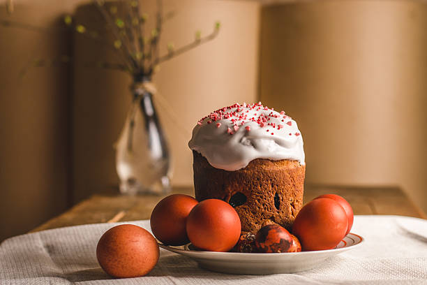 beautifully decorated Easter cake topped with icing and sprinkles sits among bright red and patterned eggs on wooden table. this vibrant setup festive spirit tradition. close up.