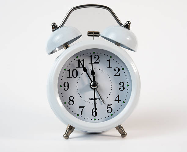 Classic white alarm clock showing time close to midnight. Perfect for New Year countdown or time management themes.