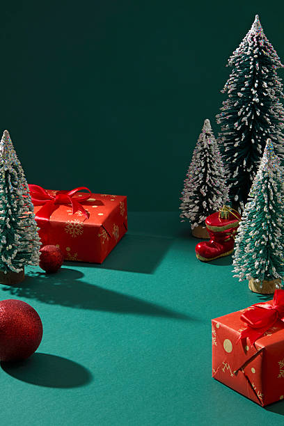 istock Christmas setup with red gift boxes, baubles, and Christmas trees on green background. Minimalist layout suitable for winter campaign visuals and social media ads. 2245600119