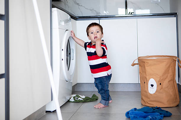 istock Naughty one-year-old baby playing with the washing machine 2245600771