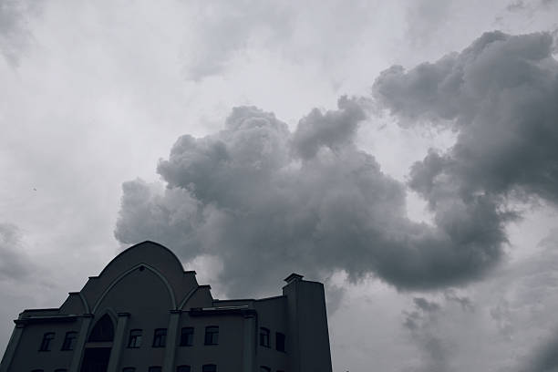 Dark, swirling clouds hover above a contemporary structure, enhancing the dramatic ambiance of the scene, with architectural features highlighted against the overcast sky