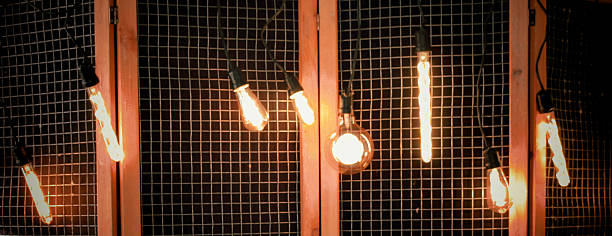 Vintage light bulbs hanging against a wooden grid background, casting warm illumination, creating a cozy atmosphere, ideal for interior design inspiration and ambiance enhancement