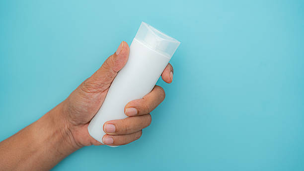 human hand grips unlabelled cosmetic container for mockup.