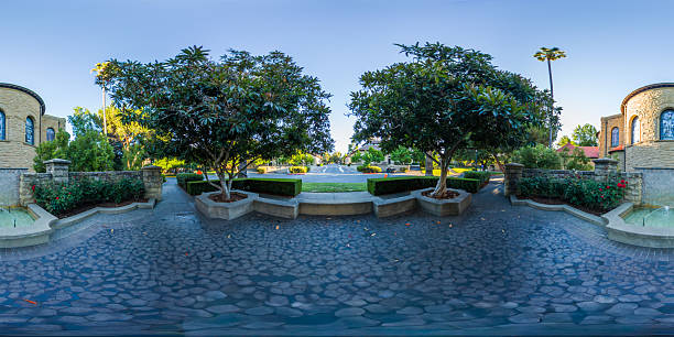 360-degree panorama of the Stanford University campus during golden hour. The paved area features symmetrical trees and manicured hedges, with classic architecture visible in the background.