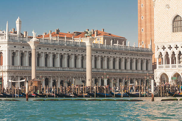 Venice, Italy - February 14, 2020: Library, St. Marco column and column of St. Theodor on St. Marco square and gondolas on water, Venice, Italy.