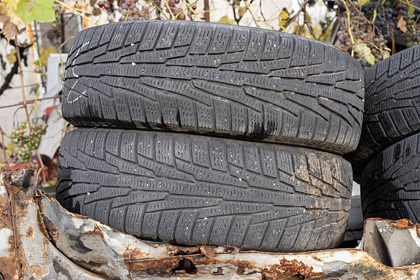 Stack of two used car tires on rusty metal background. Automotive recycling and repair concept showing detailed tread texture and vehicle maintenance theme.