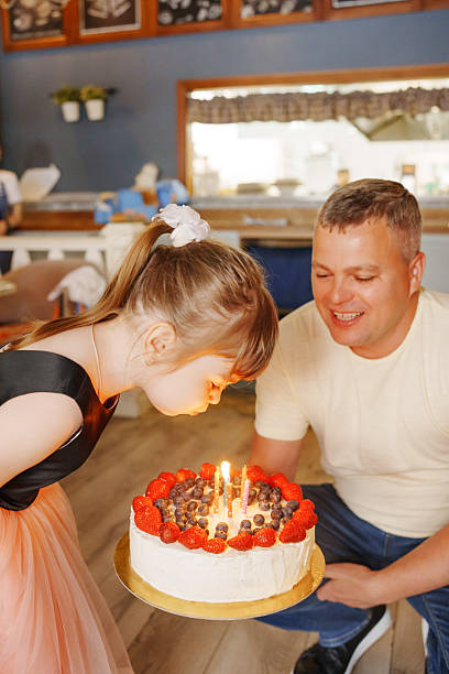 istock Girl makes a wish while blowing out birthday cake candles 2245617342