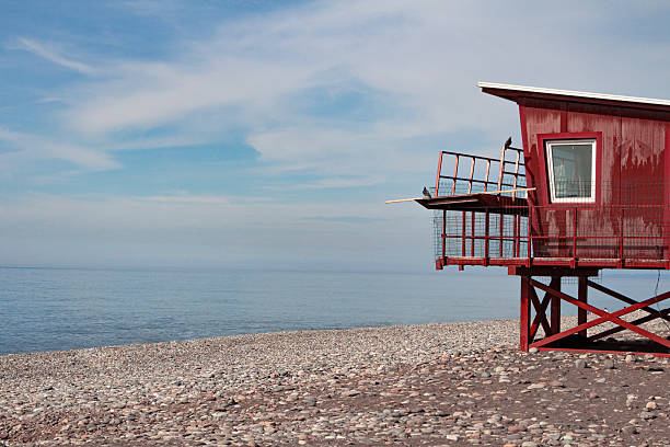 istock Red lifeguard tower on a pebble beach by the sea 2245617581