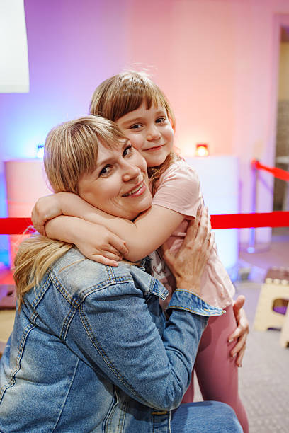 istock Mother and daughter share a warm hug at a fun event 2245618653