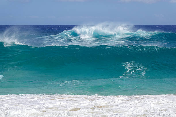 istock Powerful emerald green wave cresting with white spray against blue horizon 2245619972