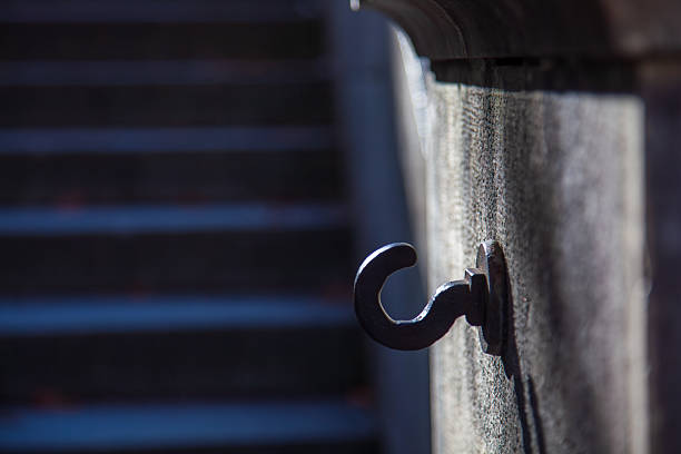 The metal hooks cast unique light and shadow on the stone wall, showcasing the beauty of architectural details and visual symbolism.