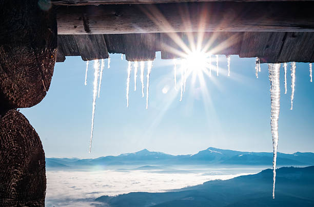Spectacular icicles shine in sun against blue sky. Splendid view with ice icicles hanging from roof of house. Christmas holiday concept. Vibrant photo wallpaper. Happy New Year! Beauty of earth.