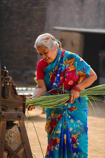 Old indian farmers couple using grass cutting machine at home.