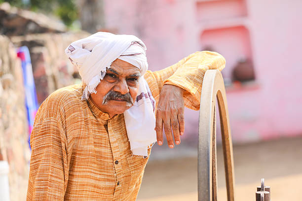 Two old indian farmers using grass cutting machine at home.