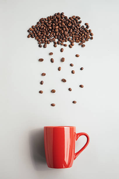 istock Coffee beans arrange with rainy cloud shape and raining to red coffee cup on gray background. Drink coffee in rainy day concept. 2245631757