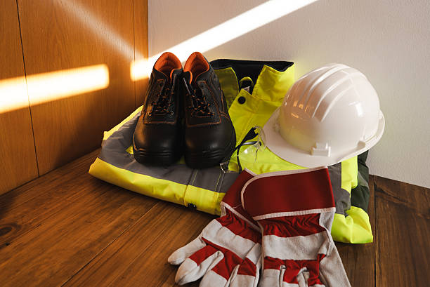 Personal protective equipment including hard hat, safety boots, high-visibility vest, and work gloves, representing worker safety