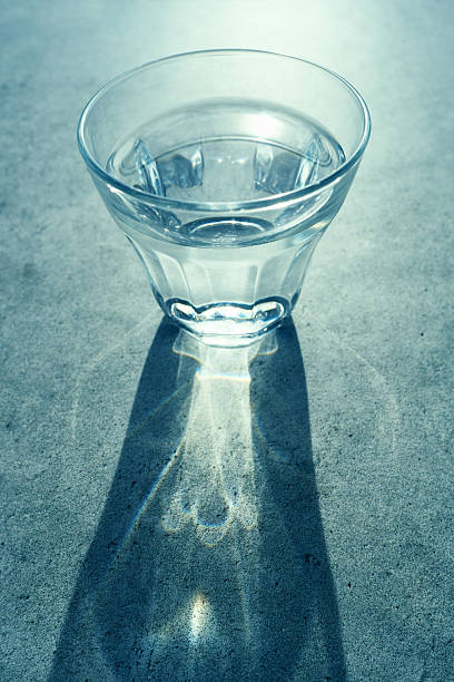 Glass of back lit clear drinking water on concrete surface