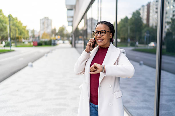 istock Professional businesswoman checking time while talking on phone 2245635426
