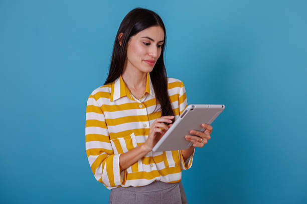 istock Woman working on tablet against blue background, focused on digital content and online communication 2245636611