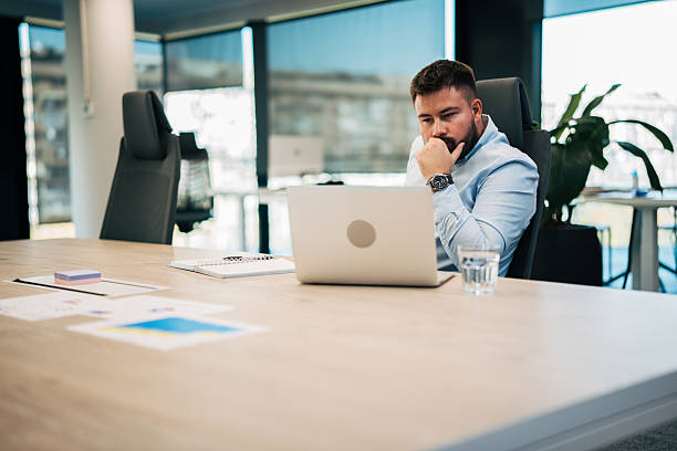 istock Businessman thinking while working on laptop in modern office 2245636826