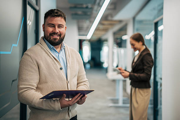 istock Confident businessman smiling in modern office hallway 2245638332