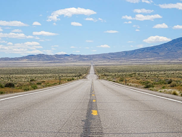 istock Road 50 traversing the vast plains in late spring, Nevada, with distant snow mountains 2245640217