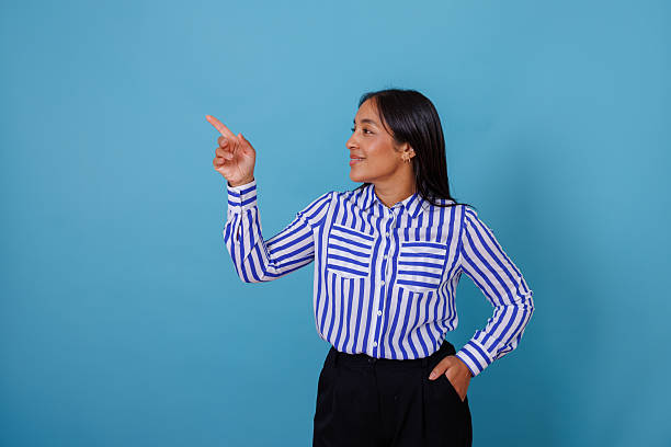 istock Young multiracial woman smiling, pointing finger up, providing copyspace for important message or product presentation 2245640767