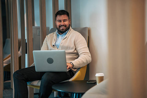 istock Smiling man working on laptop in modern office lounge 2245641627