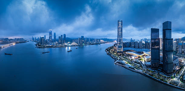istock Panoramic view of a modern waterfront city skyline with illuminated buildings and reflection in the water during blue hour in Zhuhai. 2245643604