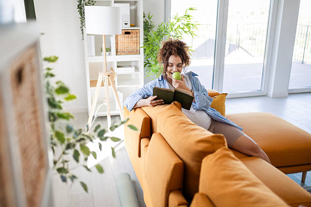 istock Pregnant Woman Having Peaceful Reading Moment on Sofa While Eating Apple 2245644133