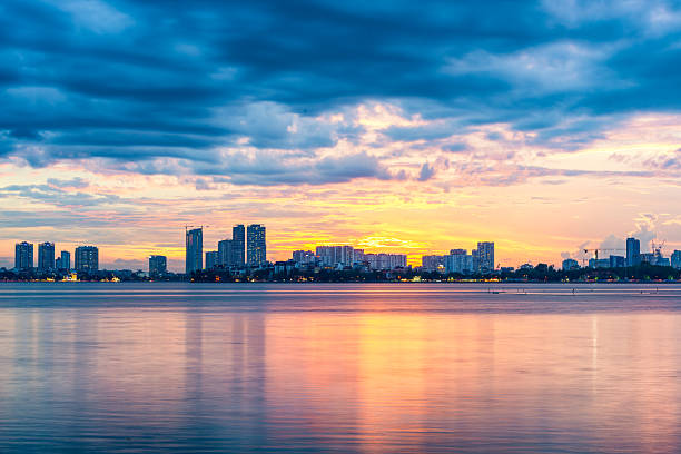 Beautiful sunset over West Lake in Hanoi, Vietnam, with colorful clouds, city skyline, and tranquil reflections on the water