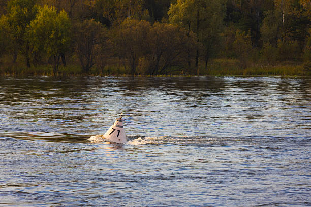 White navigation buoy in a strong stream of water on the Yenisei River, Russia. Navigation buoys are used to mark shipping lanes, hazards and other important locations for vessels. Selective focus
